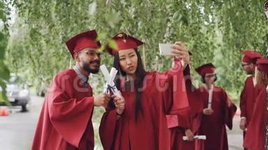 同学们都在自拍，带着<strong>毕业证书</strong>，摆着笑脸，女孩拿着智能手机，人们穿着长袍